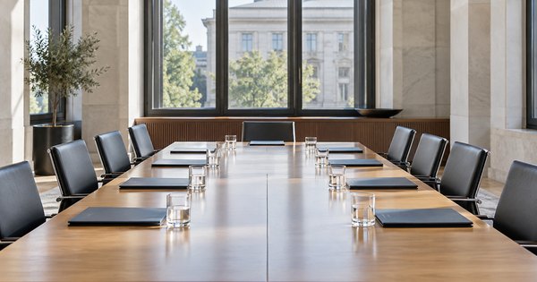 Sala de reuniones económica genérica y vacía, con carpetas cerradas y vasos de agua.